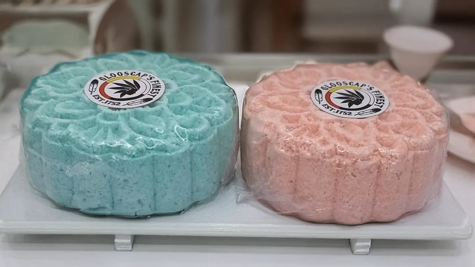 Two large Glooscap's Finest bath bombs, one teal and one pink, wrapped and labelled